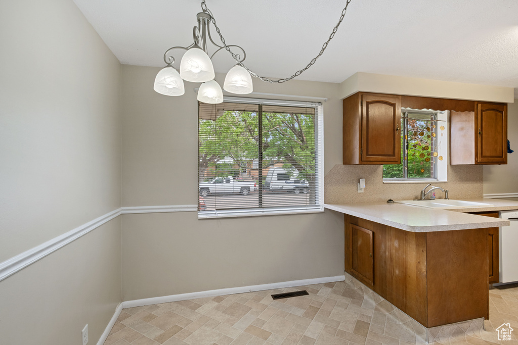 Kitchen with a sink, light countertops, plenty of natural light, and brown cabinets