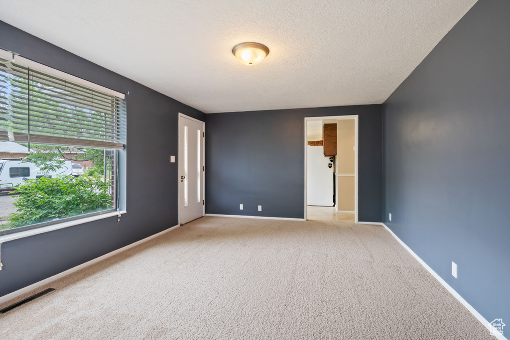 Carpeted empty room featuring baseboards and a textured ceiling