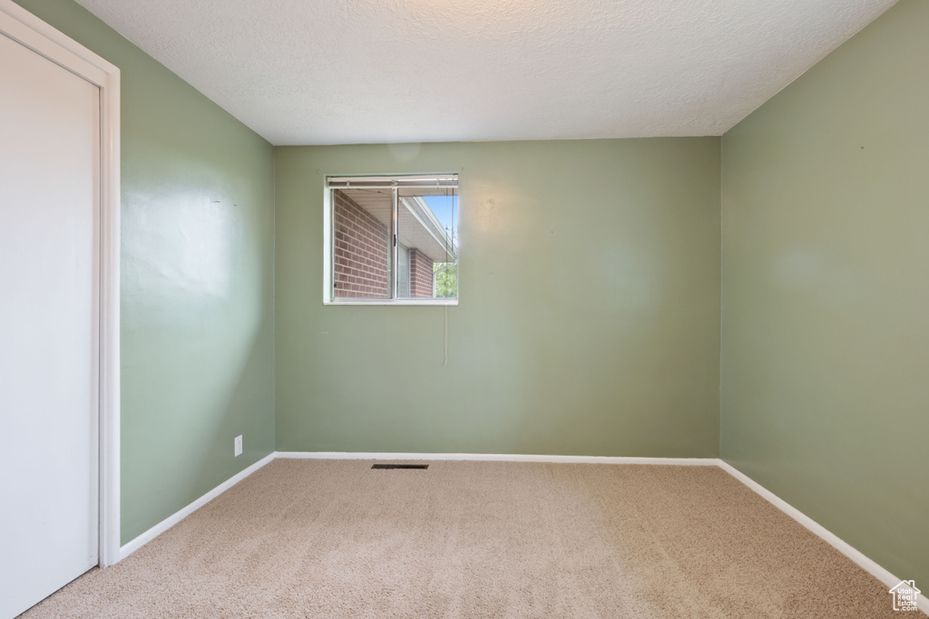 Carpeted empty room featuring baseboards and a textured ceiling