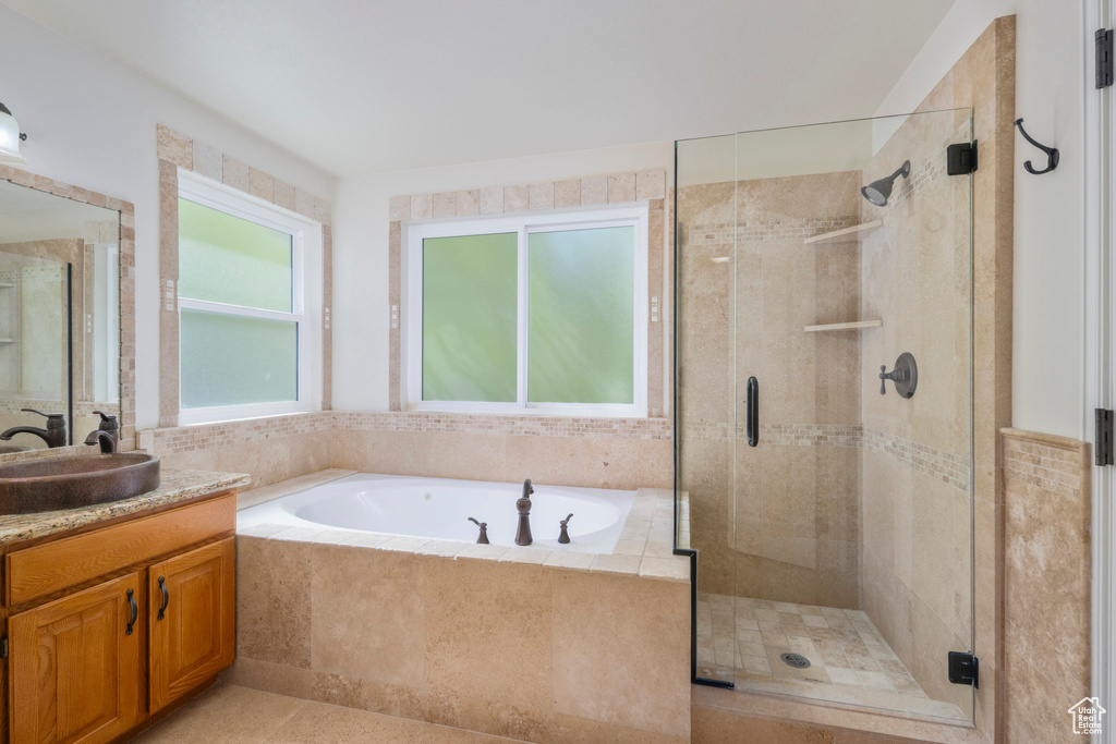 Bathroom featuring a stall shower, a bath, and vanity