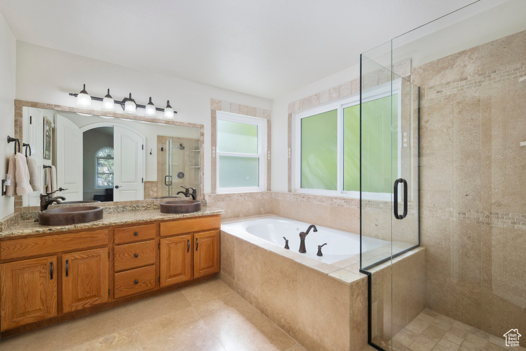 Bathroom featuring a shower stall, a bath, double vanity, and tile patterned floors