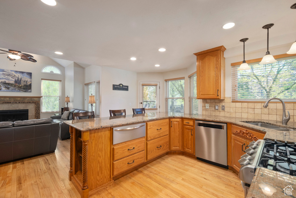 Kitchen with stainless steel dishwasher, a warming drawer, a sink, light wood-style floors, and a peninsula