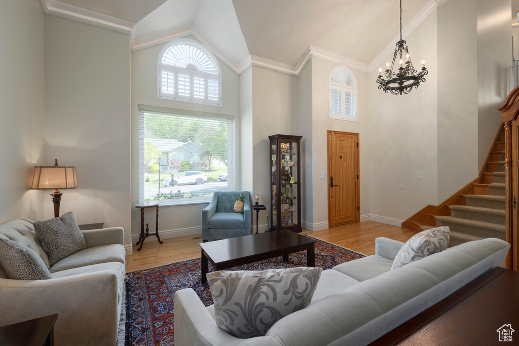 Living area with high vaulted ceiling, a chandelier, stairs, wood finished floors, and baseboards