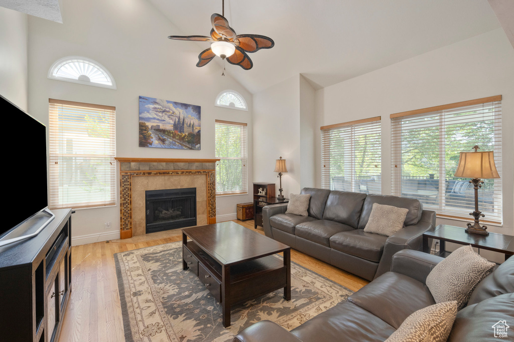Living area with healthy amount of natural light, high vaulted ceiling, ceiling fan, and light wood-style floors