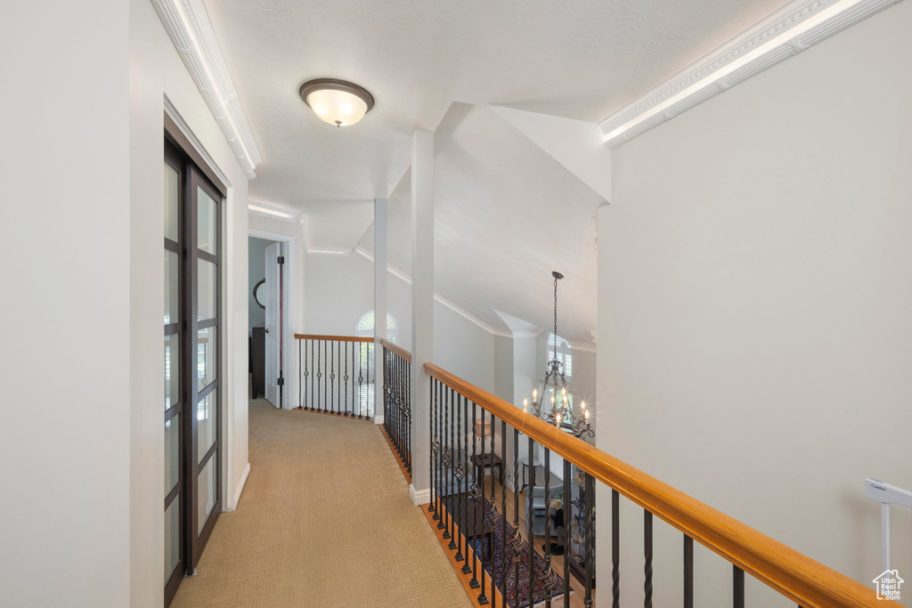 Corridor featuring an upstairs landing, light colored carpet, and a chandelier