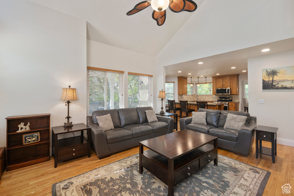 Living area featuring ceiling fan, light wood-type flooring, high vaulted ceiling, recessed lighting, and baseboards