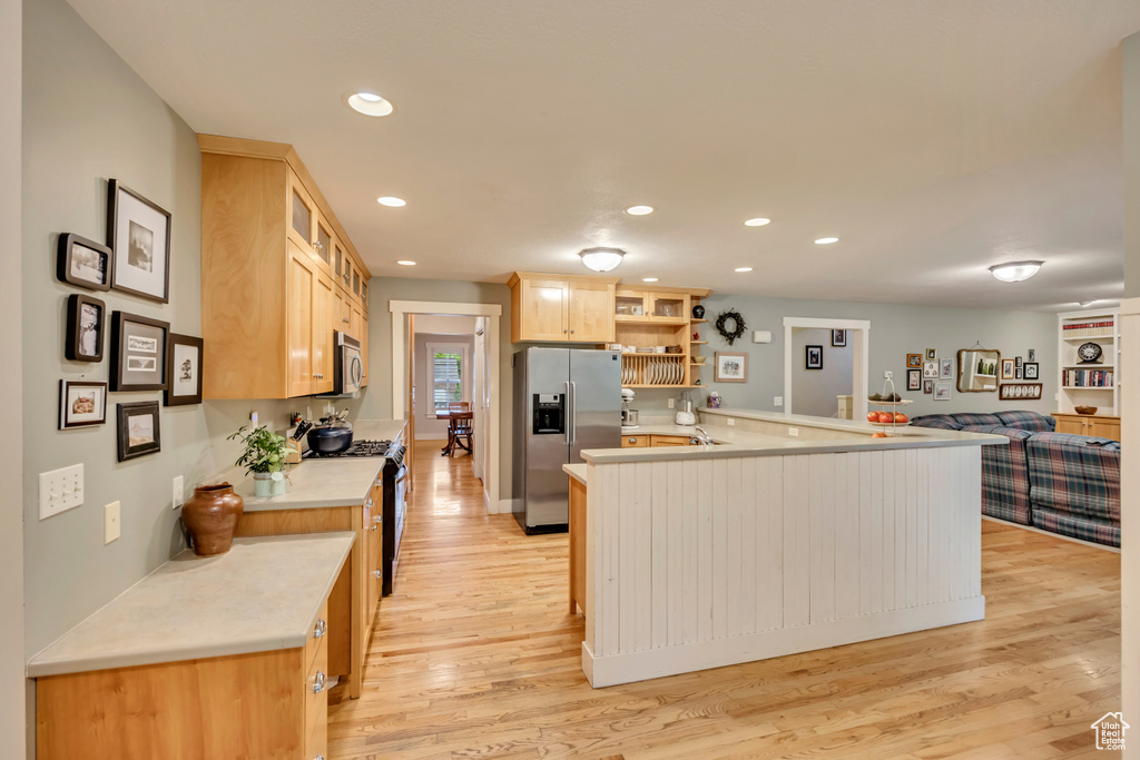 Kitchen featuring appliances with stainless steel finishes, open shelves, light wood finished floors, light countertops, and recessed lighting