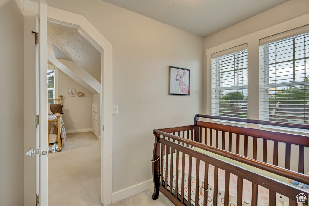 Carpeted bedroom featuring baseboards and a crib