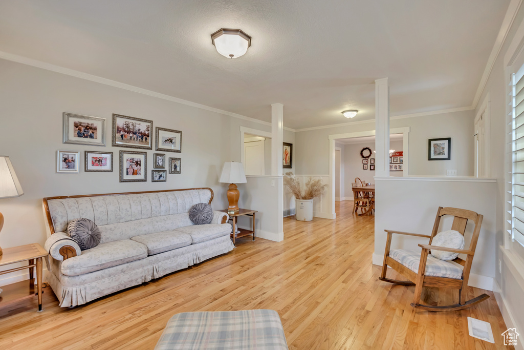 Living area with wood finished floors, crown molding, and baseboards