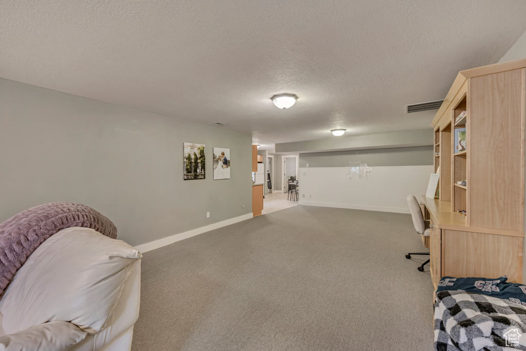 Sitting room featuring a textured ceiling, carpet floors, baseboards, and a desk