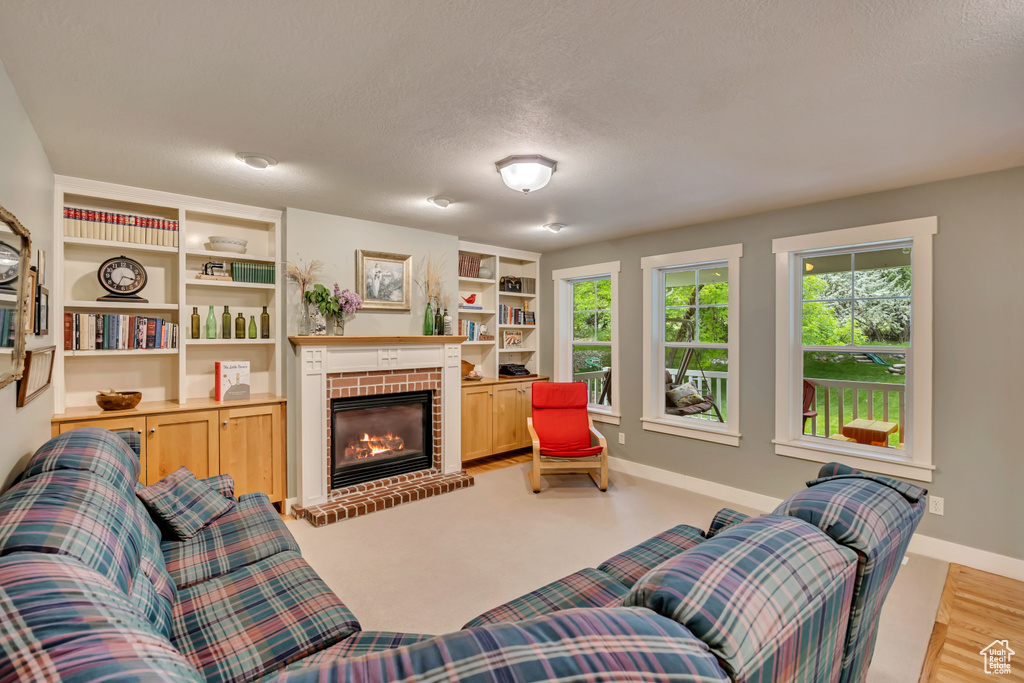 Living room with a fireplace, baseboards, built in features, and a textured ceiling