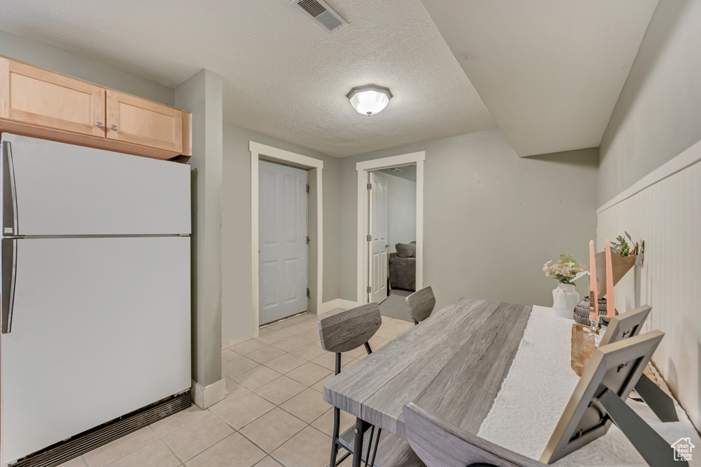 Dining space with light tile patterned flooring and a textured ceiling