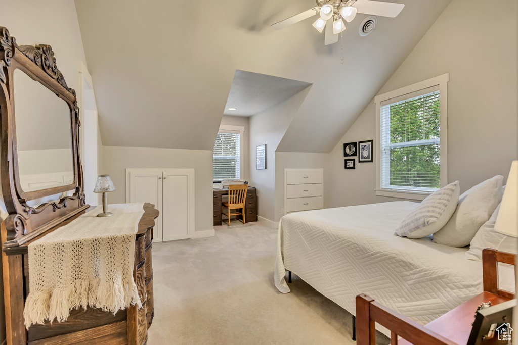 Bedroom featuring light colored carpet, lofted ceiling, multiple windows, ceiling fan, and baseboards