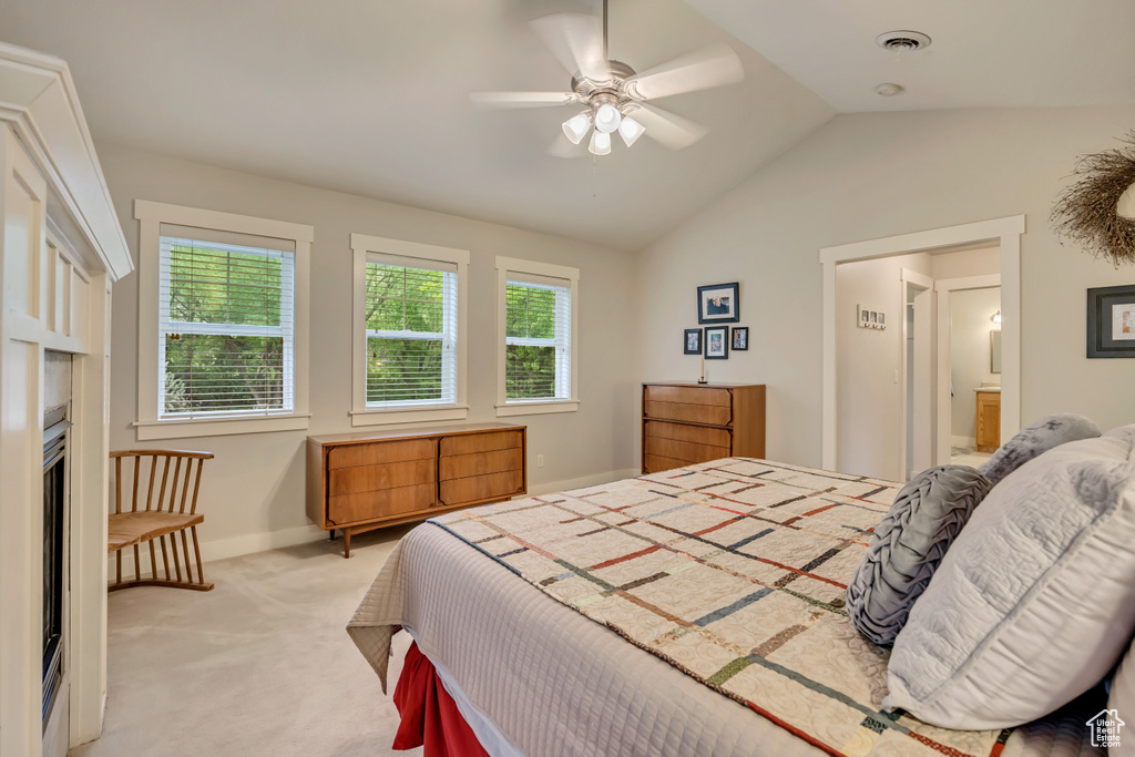 Bedroom featuring light colored carpet, lofted ceiling, baseboards, ceiling fan, and connected bathroom