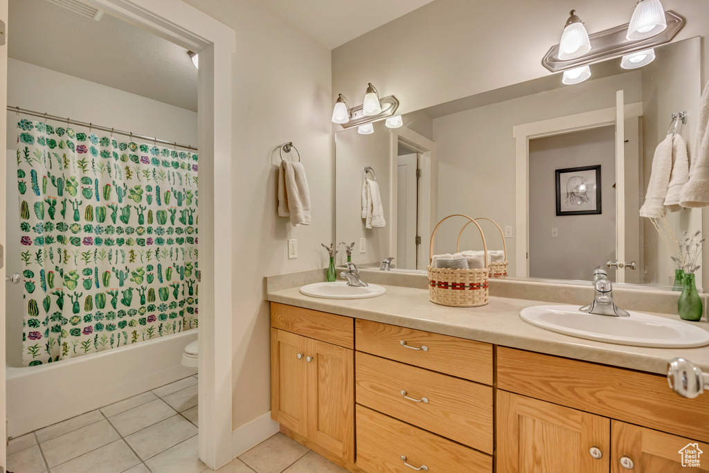 Full bathroom with tile patterned floors, double vanity, toilet, and shower / tub combo with curtain