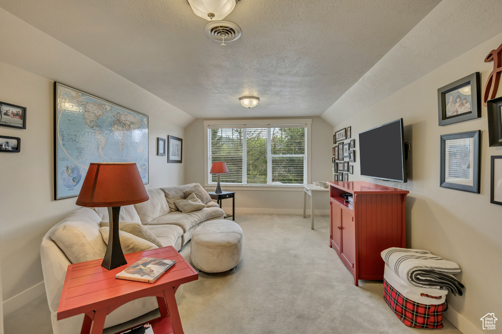 Living room featuring a textured ceiling, baseboards, lofted ceiling, and light carpet