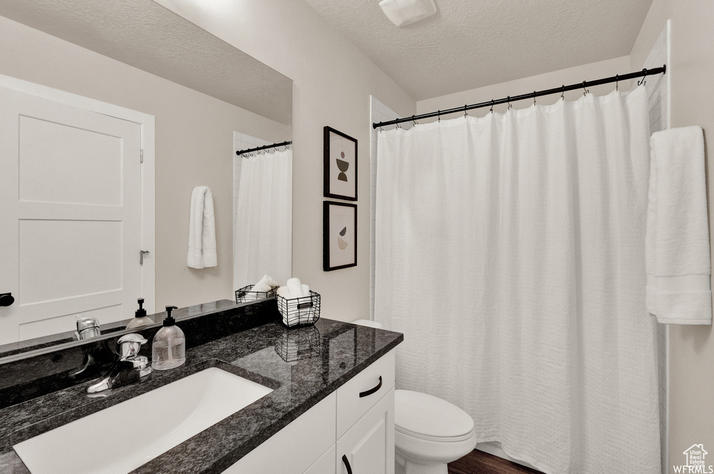 Full bath with toilet, vanity, and a textured ceiling