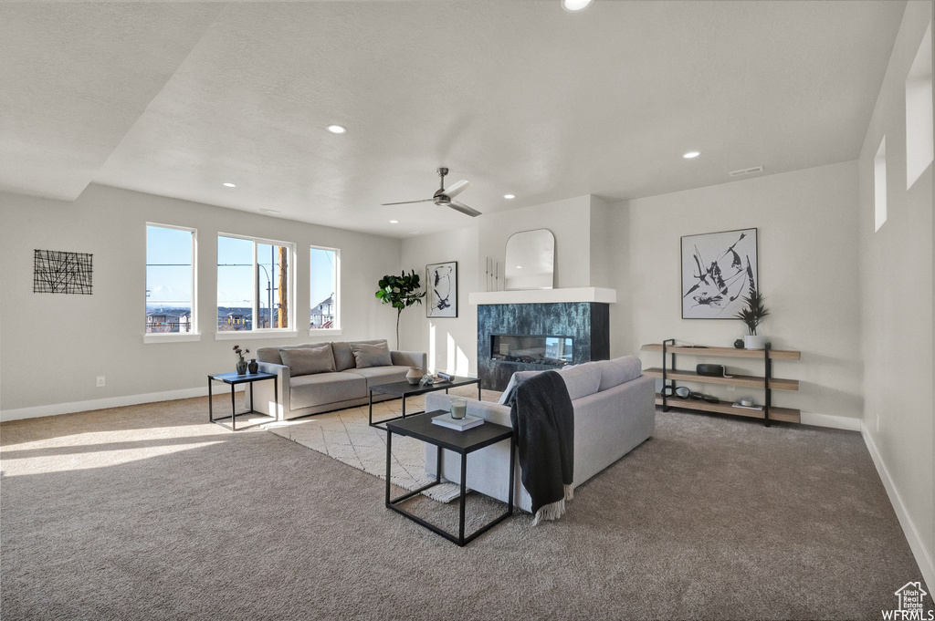 Living area featuring light carpet, a premium fireplace, baseboards, recessed lighting, and ceiling fan