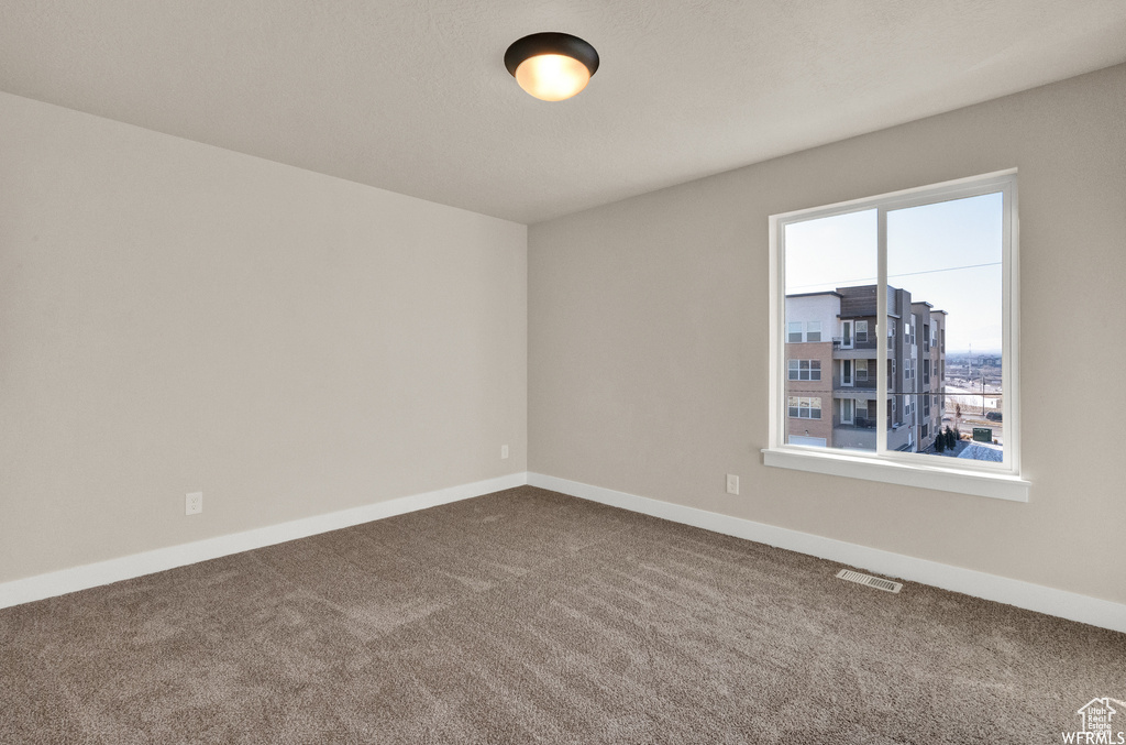 Empty room featuring dark colored carpet and baseboards