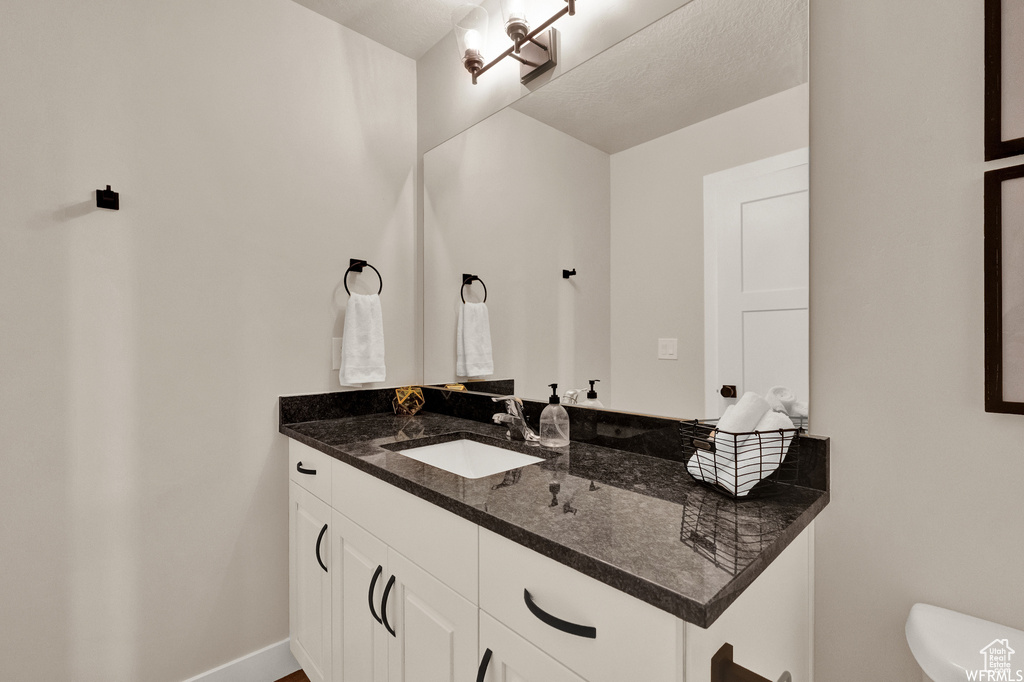 Bathroom with vanity, toilet, and baseboards