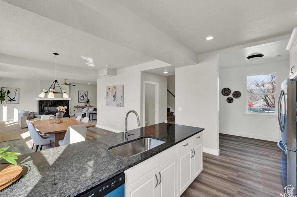 Kitchen featuring a sink, freestanding refrigerator, open floor plan, white cabinets, and dark wood-type flooring