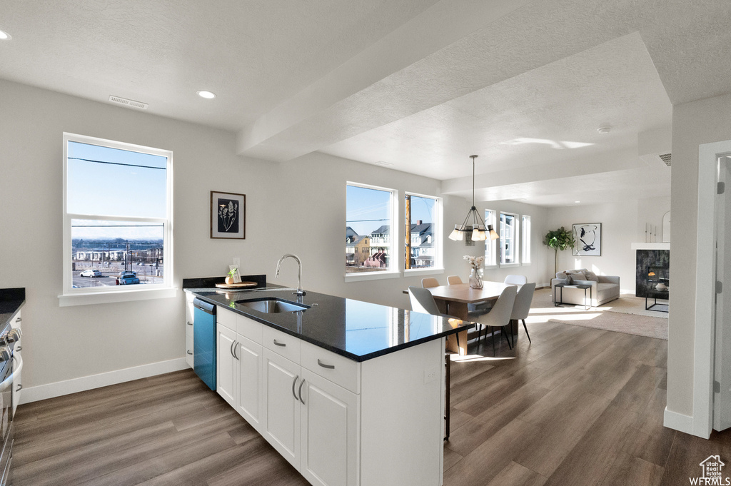Kitchen featuring a sink, dark countertops, dark wood-style flooring, baseboards, and a peninsula