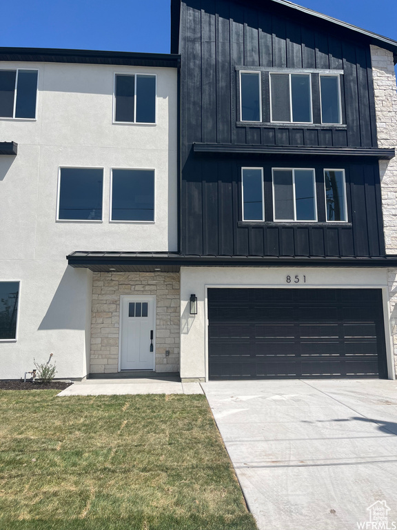 View of front of property featuring board and batten siding, an attached garage, stone siding, and concrete driveway