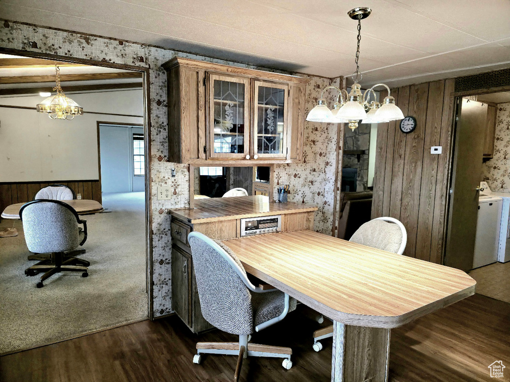 Dining area featuring a chandelier, washer and dryer, wooden walls, dark wood-style floors, and a wainscoted wall