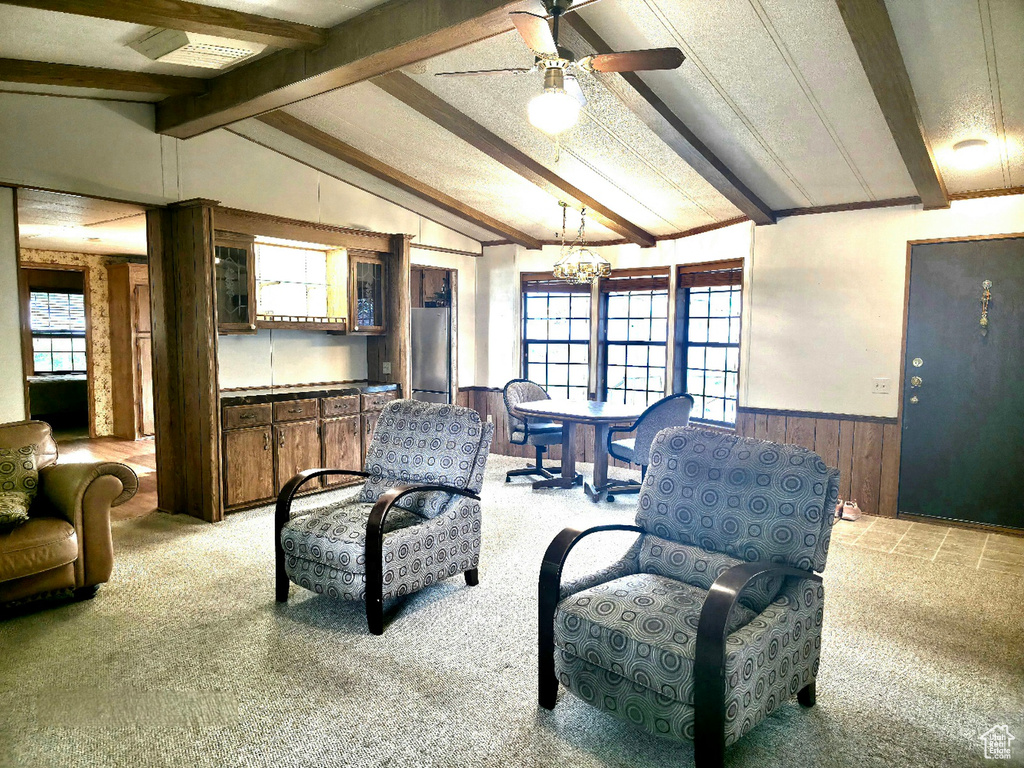 Living area featuring wainscoting, wooden walls, carpet flooring, a chandelier, and a ceiling fan