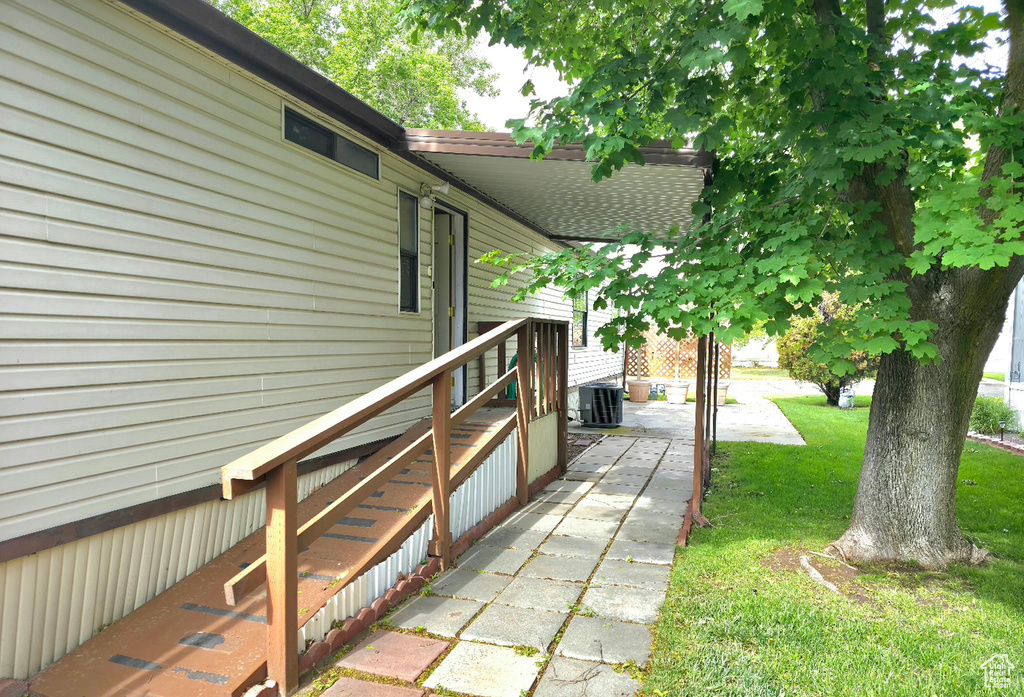 View of side of home with a yard and central AC