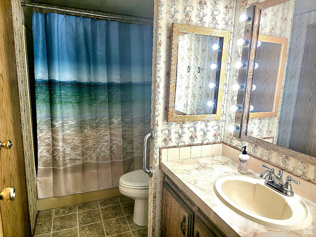 Bathroom with wallpapered walls, toilet, and vanity