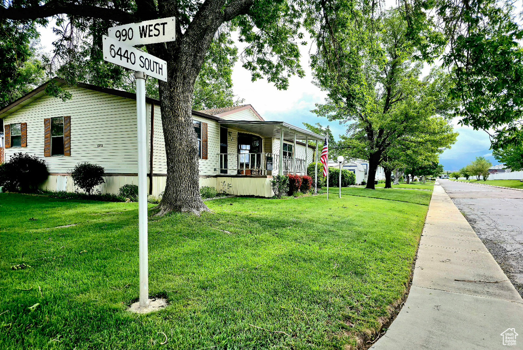 View of side of home featuring covered porch and a yard