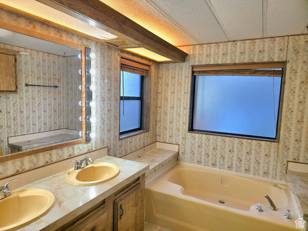 Full bathroom with wallpapered walls, a bath, and double vanity