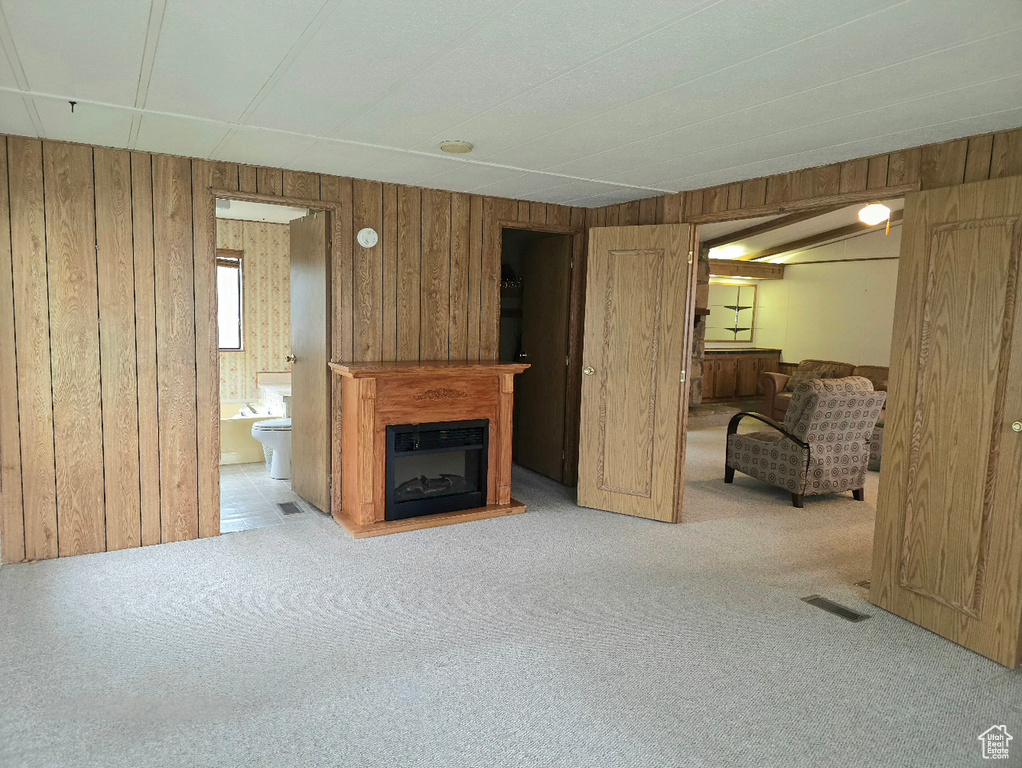 Unfurnished living room with wooden walls, carpet floors, and a glass covered fireplace