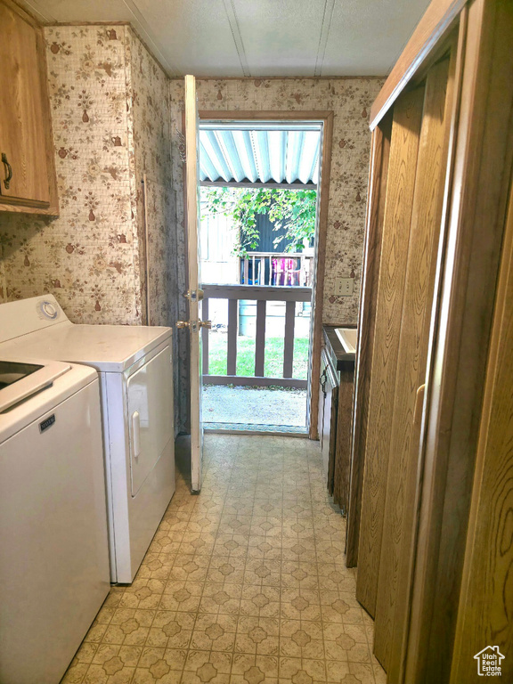Clothes washing area with separate washer and dryer, wallpapered walls, light floors, and cabinet space