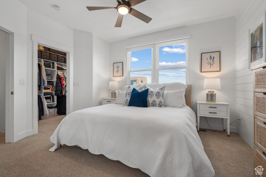 Bedroom with light colored carpet, a walk in closet, a closet, and ceiling fan
