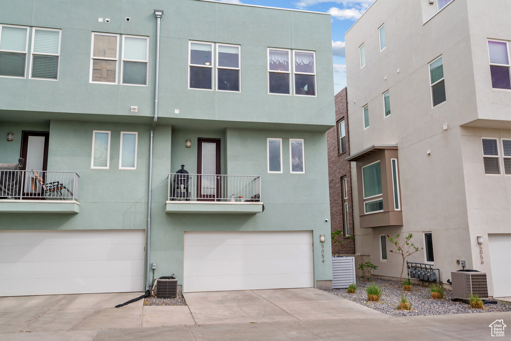 View of front of home featuring central air condition unit, stucco siding, and concrete driveway