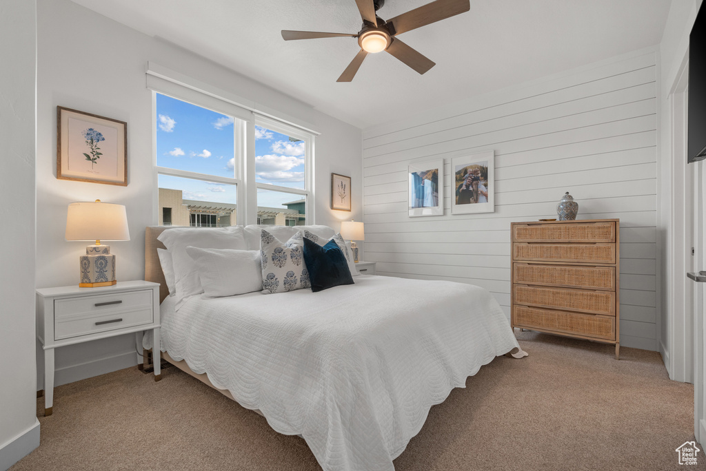 Bedroom featuring carpet, wood walls, a ceiling fan, and baseboards