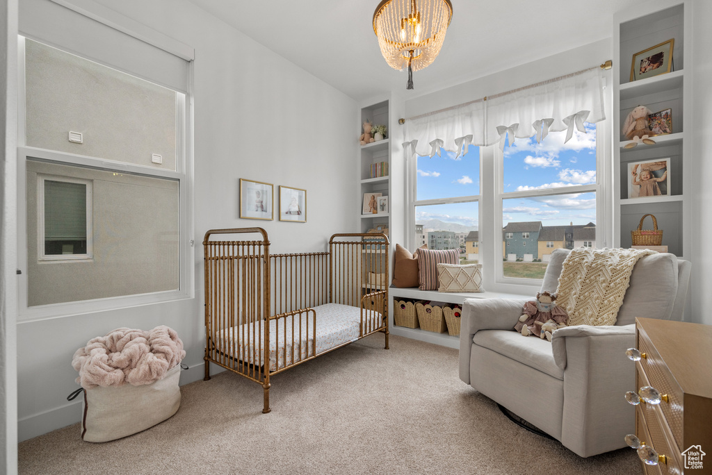 Carpeted bedroom featuring a chandelier and a nursery area