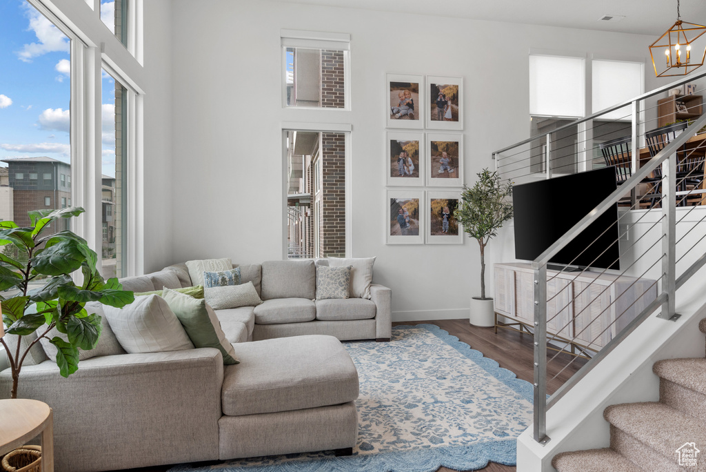 Living area with stairs, baseboards, a chandelier, wood finished floors, and a towering ceiling