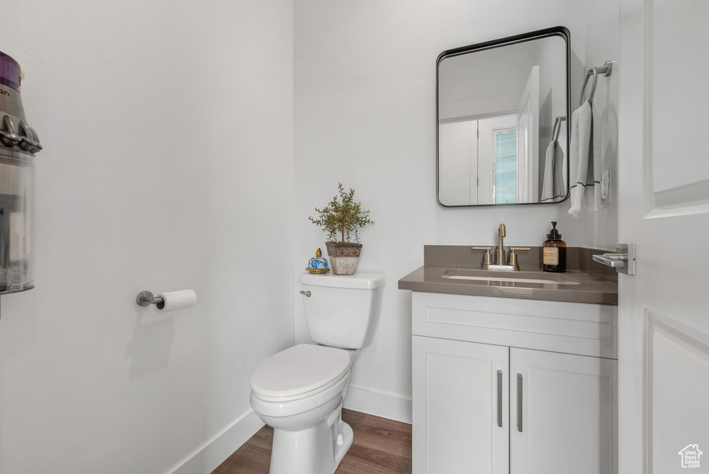 Bathroom featuring toilet, wood finished floors, baseboards, and vanity