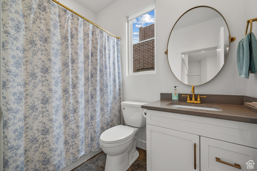 Bathroom featuring toilet, vanity, and a shower with curtain