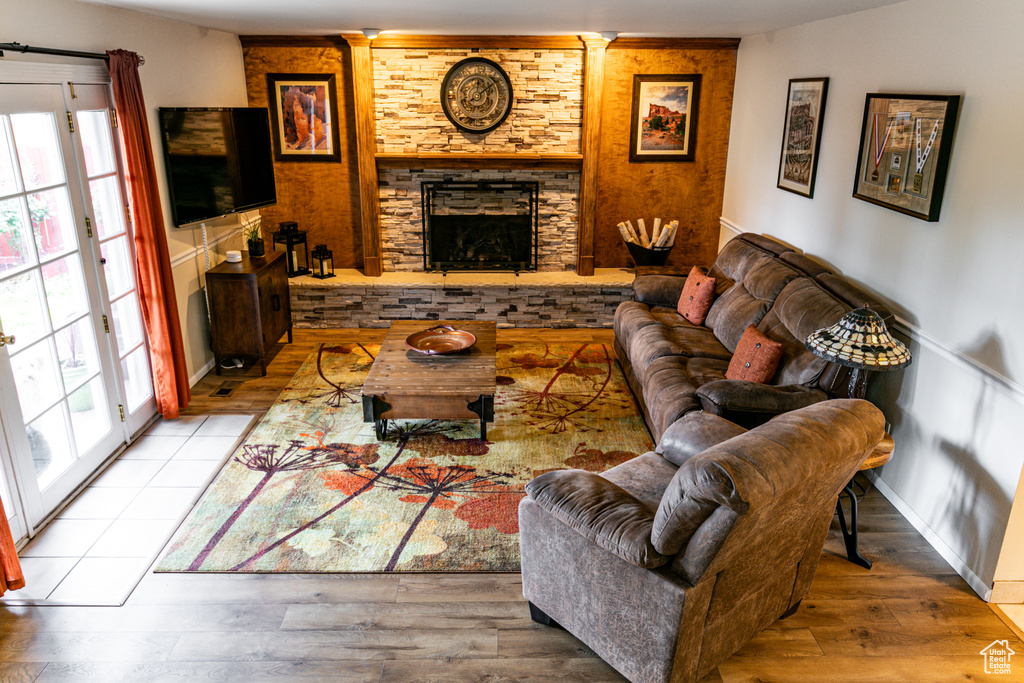 Living room featuring a stone fireplace, wood finished floors, and plenty of natural light