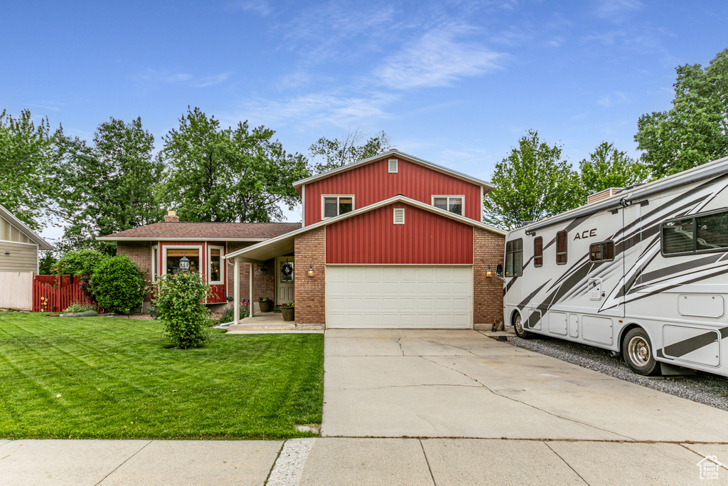 View of front of house featuring brick siding, driveway, an attached garage, and board and batten siding
