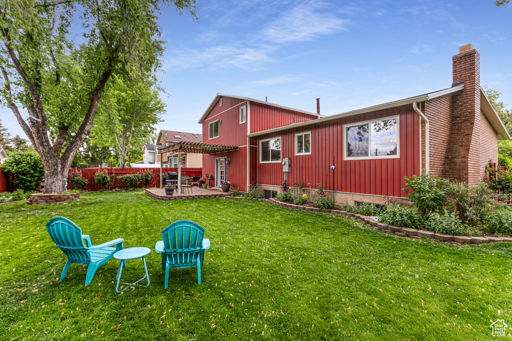 Back of property featuring a chimney, a pergola, and a patio