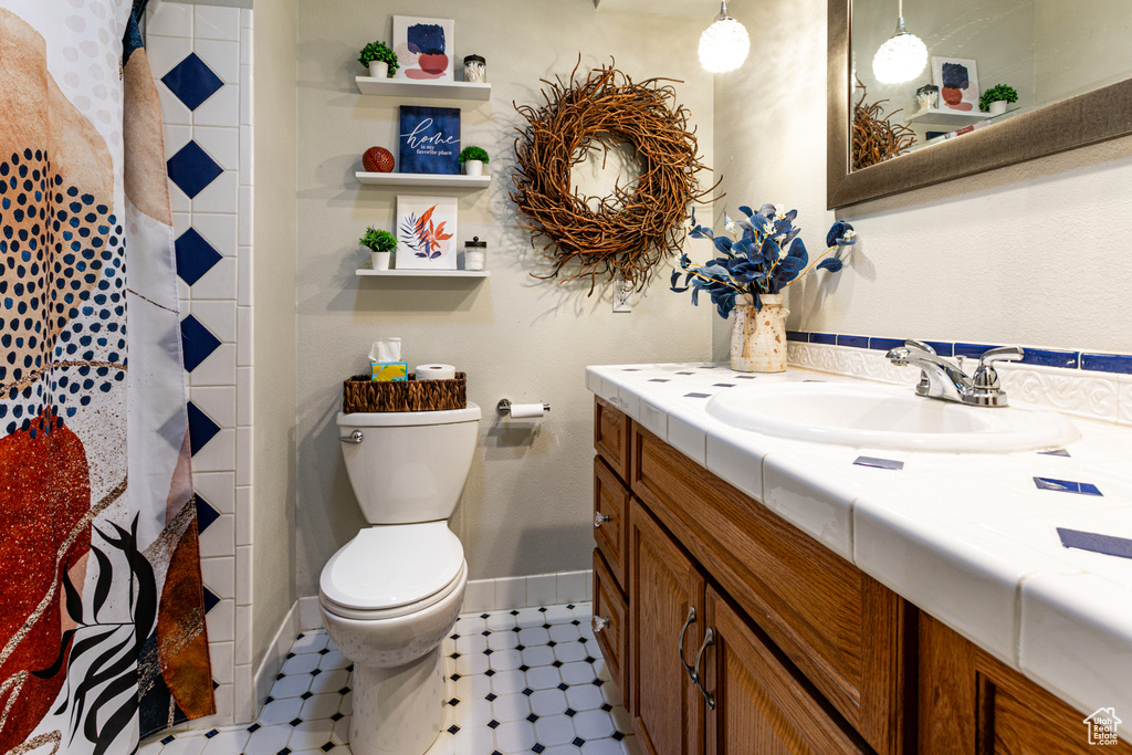 Full bath with tile patterned floors, toilet, vanity, baseboards, and a shower