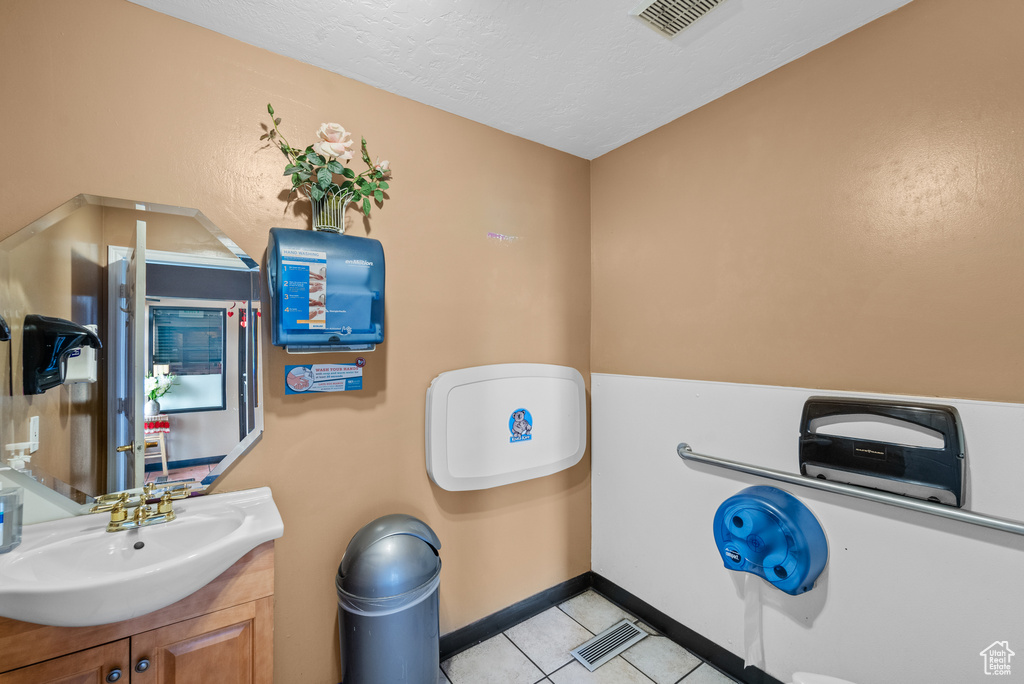 Bathroom featuring tile patterned floors, vanity, a textured ceiling, and baseboards