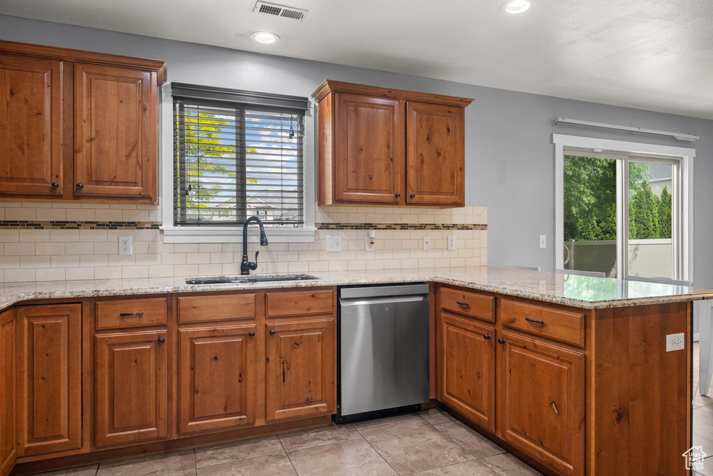 Kitchen with dishwasher, a sink, a peninsula, brown cabinets, and plenty of natural light