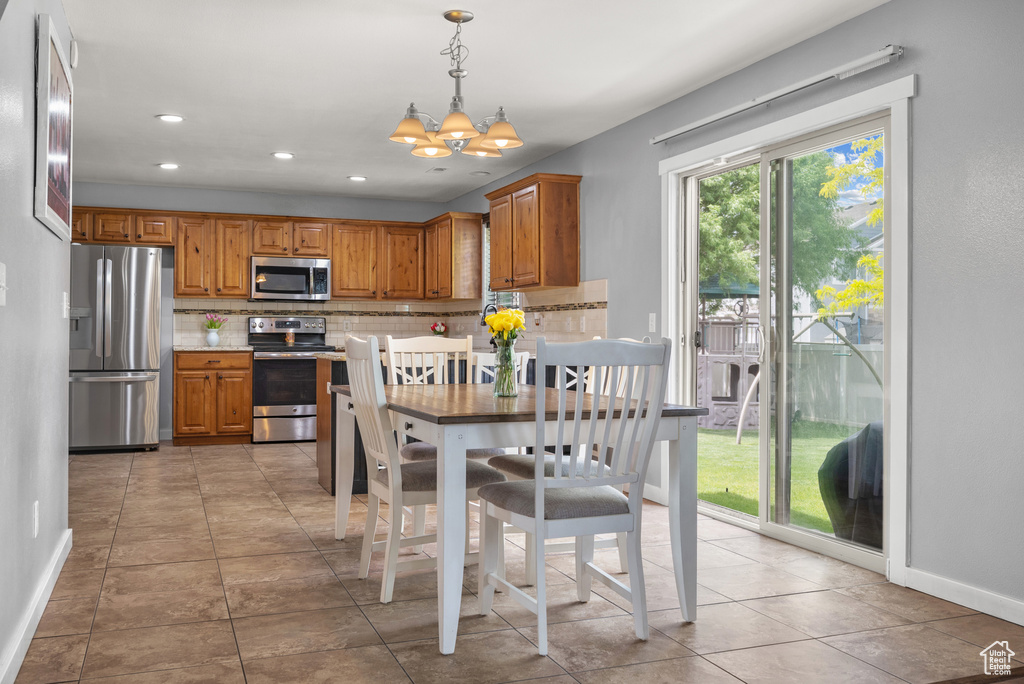 Dining area with a chandelier, baseboards, light tile patterned floors, and recessed lighting