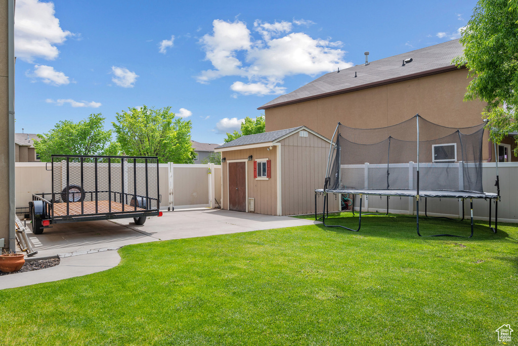 View of yard featuring a trampoline, a patio, a storage unit, and an outdoor structure